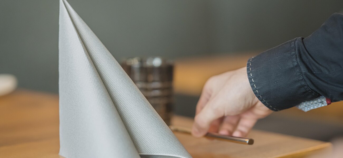 Gefaltete Stoffserviette steht aufrecht auf einem Holztisch im Restaurant